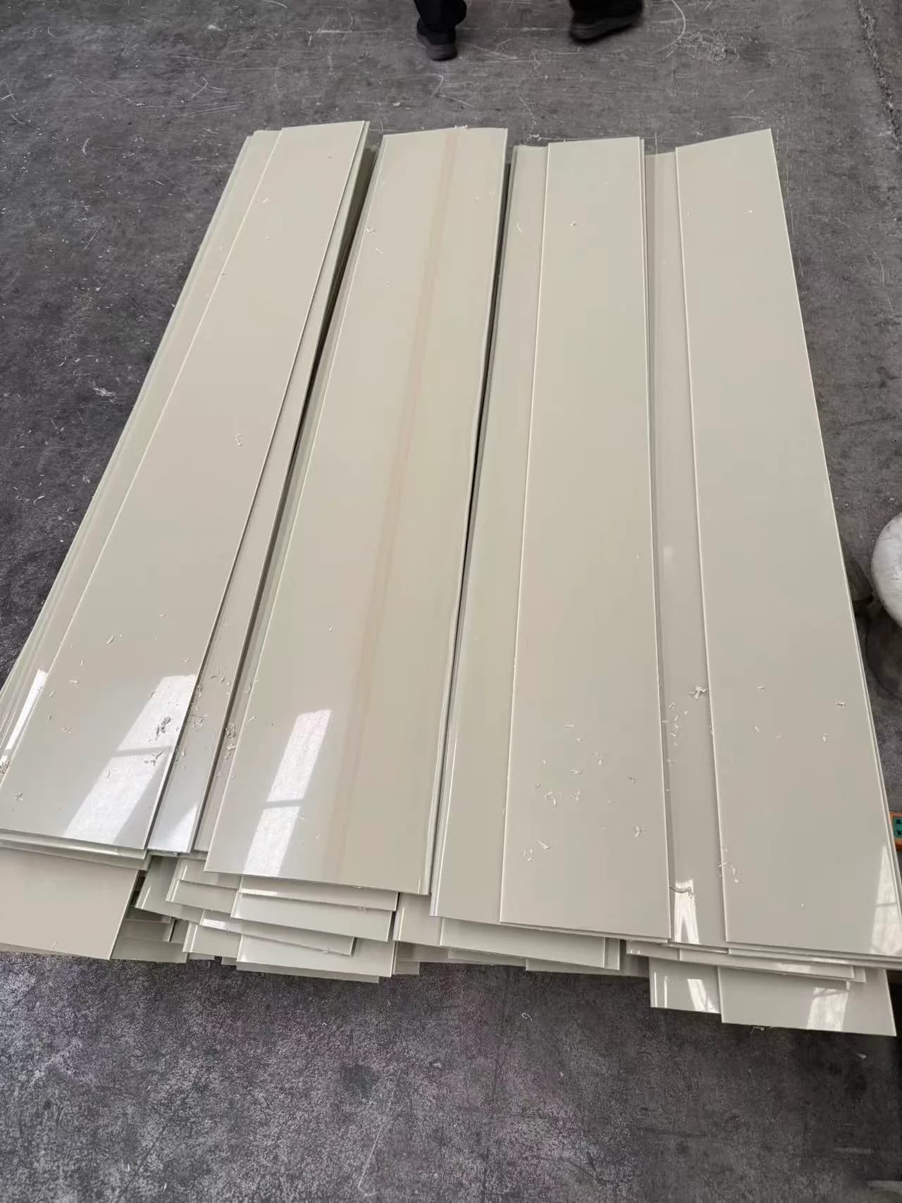 Long cut plastic components stacked on the workshop floor