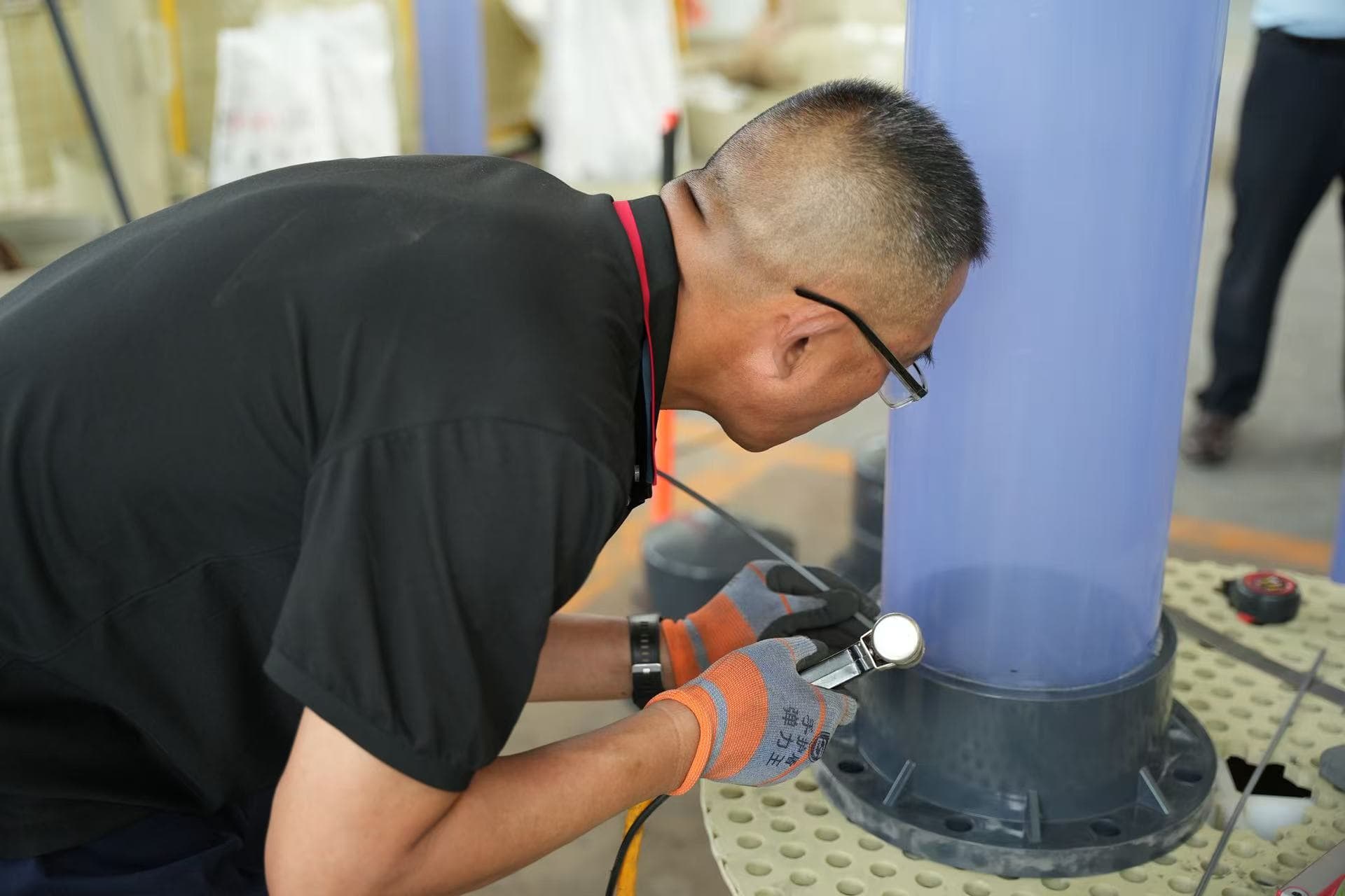 Xin Longdi worker welding a plastic pipe connection in the workshop