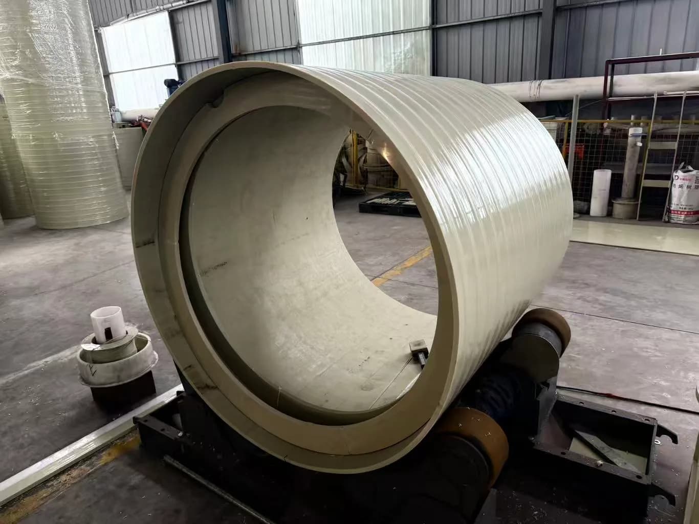 Large plastic cylinder resting on fabrication rollers in the Xin Longdi workshop